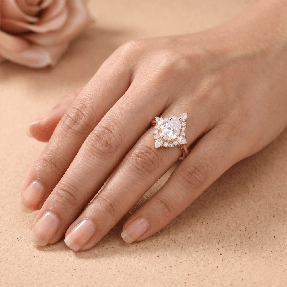 A close-up of a hand wearing a rose gold ring with a large clear gemstone surrounded by smaller stones, set against a warm beige background.
