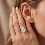 A close-up lifestyle shot of a woman wearing a diamond ring with a rose gold band, resting her hand near her ear.