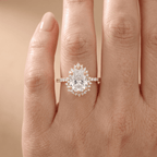 A close-up of a hand wearing a rose gold halo engagement ring with a large round-cut center stone and smaller accent stones.