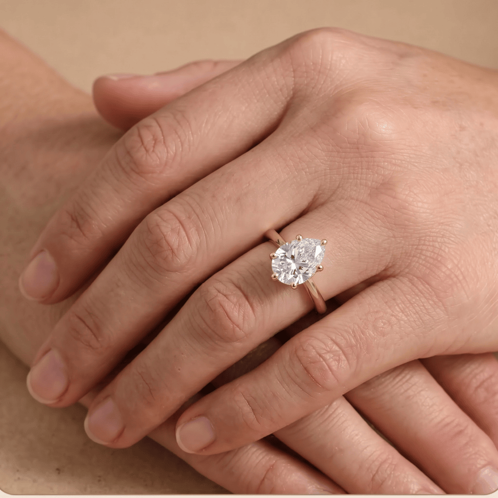 Pear shaped solitaire diamond ring worn on hand, 14K gold band