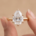 Pear shaped solitaire diamond ring worn on hand, 14K gold band