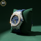 Luxury watch with diamond-studded bezel on a green cushion, branded 'JBR'.