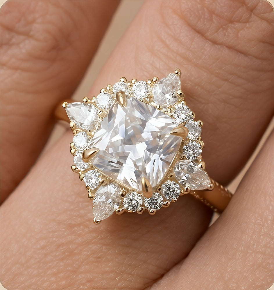 A gold ring with a large clear cushion-shaped center stone and surrounding pear and round diamonds, shown worn on a hand.