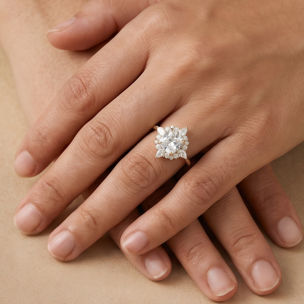 A close-up of a person's hands resting on a beige surface, wearing a silver-toned cluster ring with a clear central gemstone.