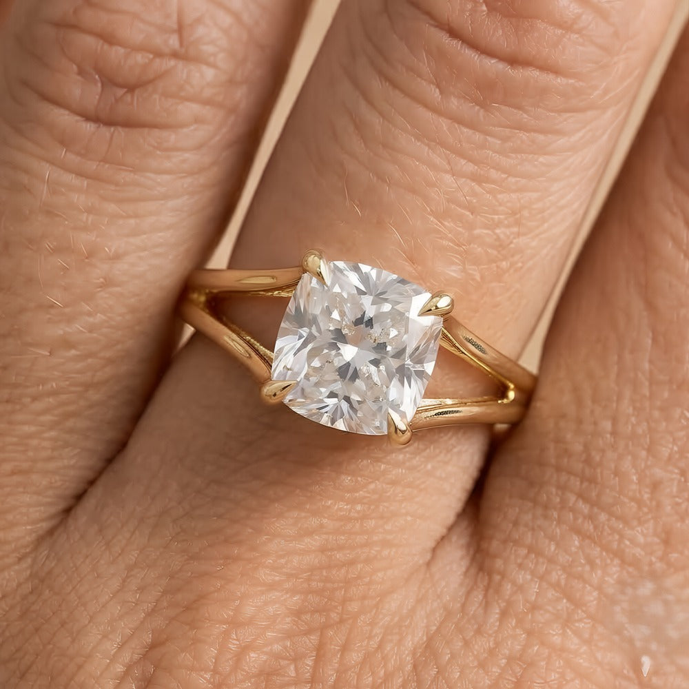 A yellow gold ring with a cushion-cut clear gemstone set on a person's finger, shown in a close-up shot.