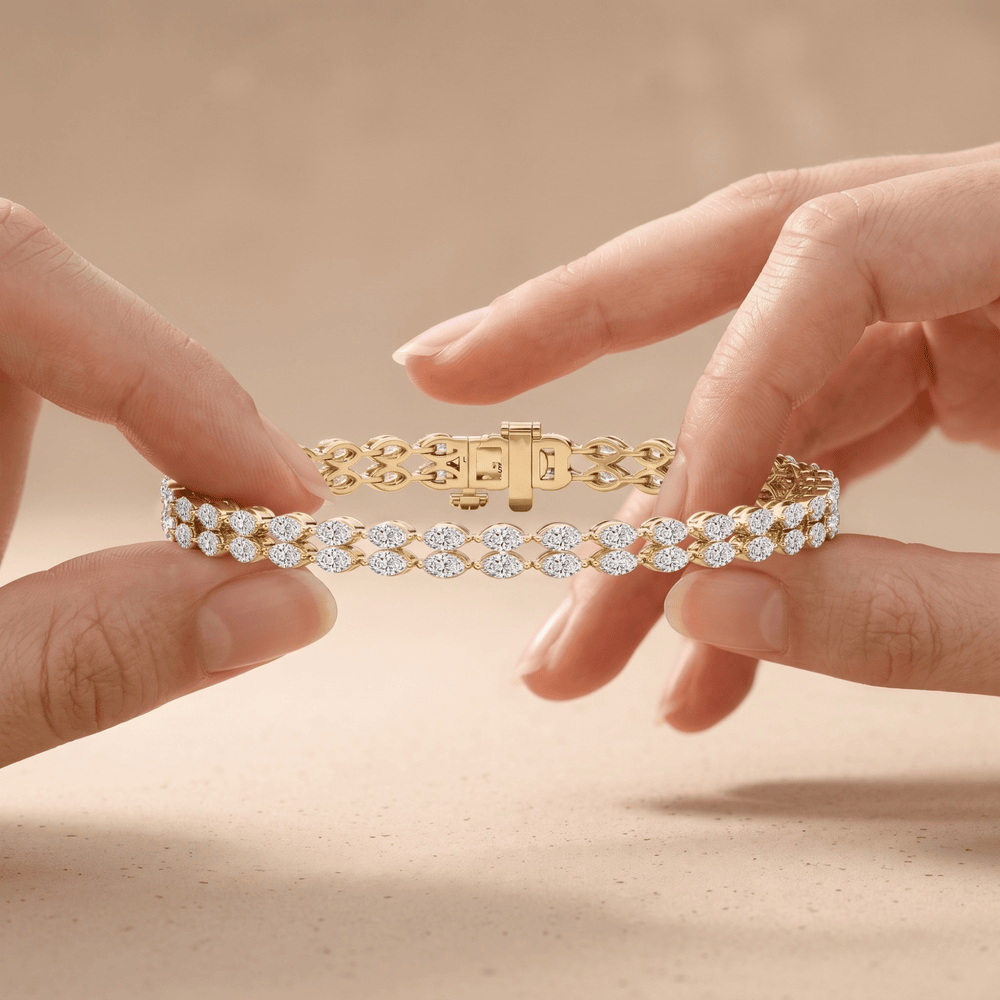 A close-up of a gold tennis bracelet with clear round-cut stones, held between two hands against a soft beige background.