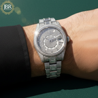 Silver diamond-encrusted watch on a wrist with a blurred green background