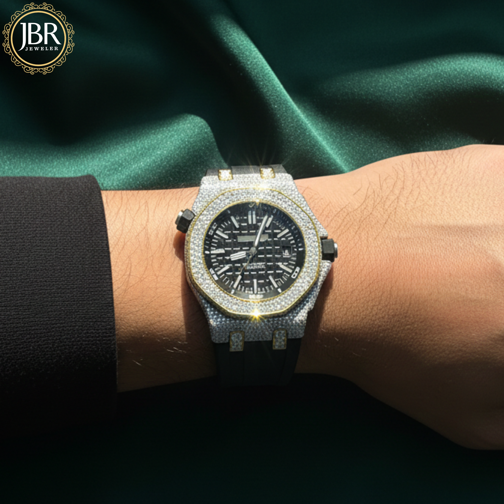 Luxury watch with diamond bezel on a wrist against a green satin background, featuring JBR Jewellers 