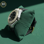 Luxury watch with diamond accents on a green cushion, branded 'JBR Jewels'.