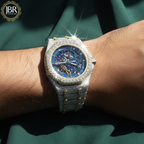 Luxury watch with diamond-studded case on a wrist against a green fabric background, featuring JBR Jeweler