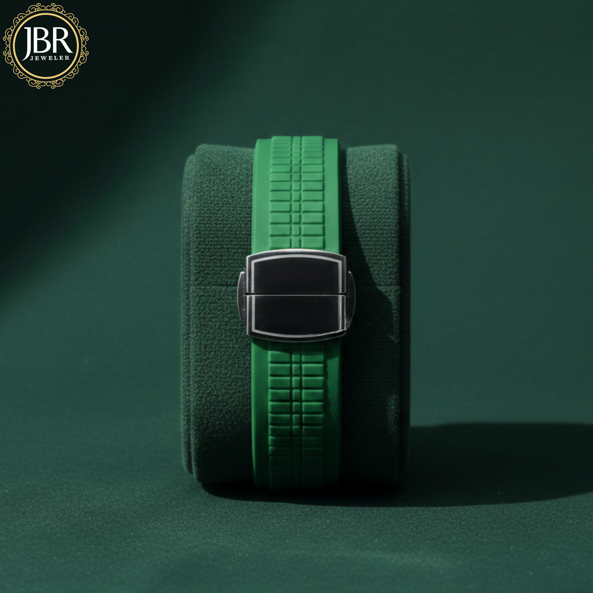 Green belt with a silver buckle on a dark green background, featuring the JBR Jeweler