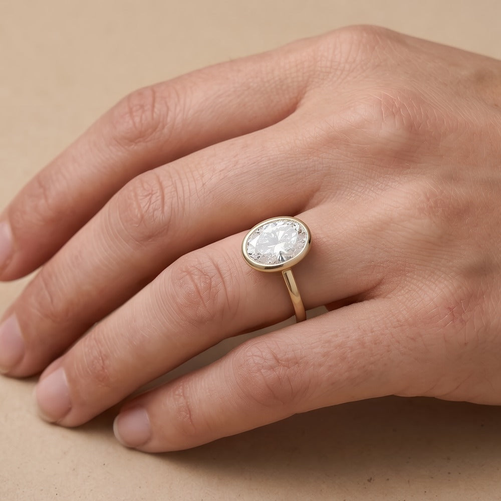 Bezel set oval diamond proposal ring on hand Finger