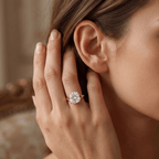 A close-up lifestyle shot of a woman's hand and ear wearing a radiant diamond engagement ring with a rose gold band.