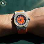 Luxury watch with orange strap and blue face on a wrist, branded 'JBR'.