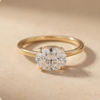 A classic solitaire engagement ring featuring a round brilliant-cut diamond set in a polished yellow gold band, resting on a textured beige surface.
