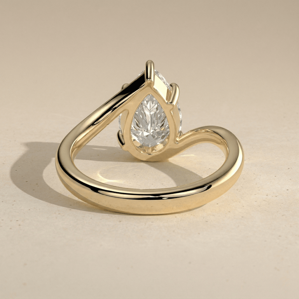 Pear diamond bypass engagement ring with curved gold band
