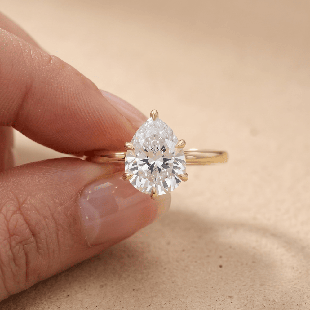 Pear cut diamond engagement ring on model's hand