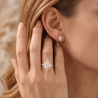 A close-up lifestyle shot of a woman wearing a gold ring with a diamond halo and a matching diamond stud earring. The ring features a marquise-cut center stone surrounded by a diamond cluster, set on a gold band.