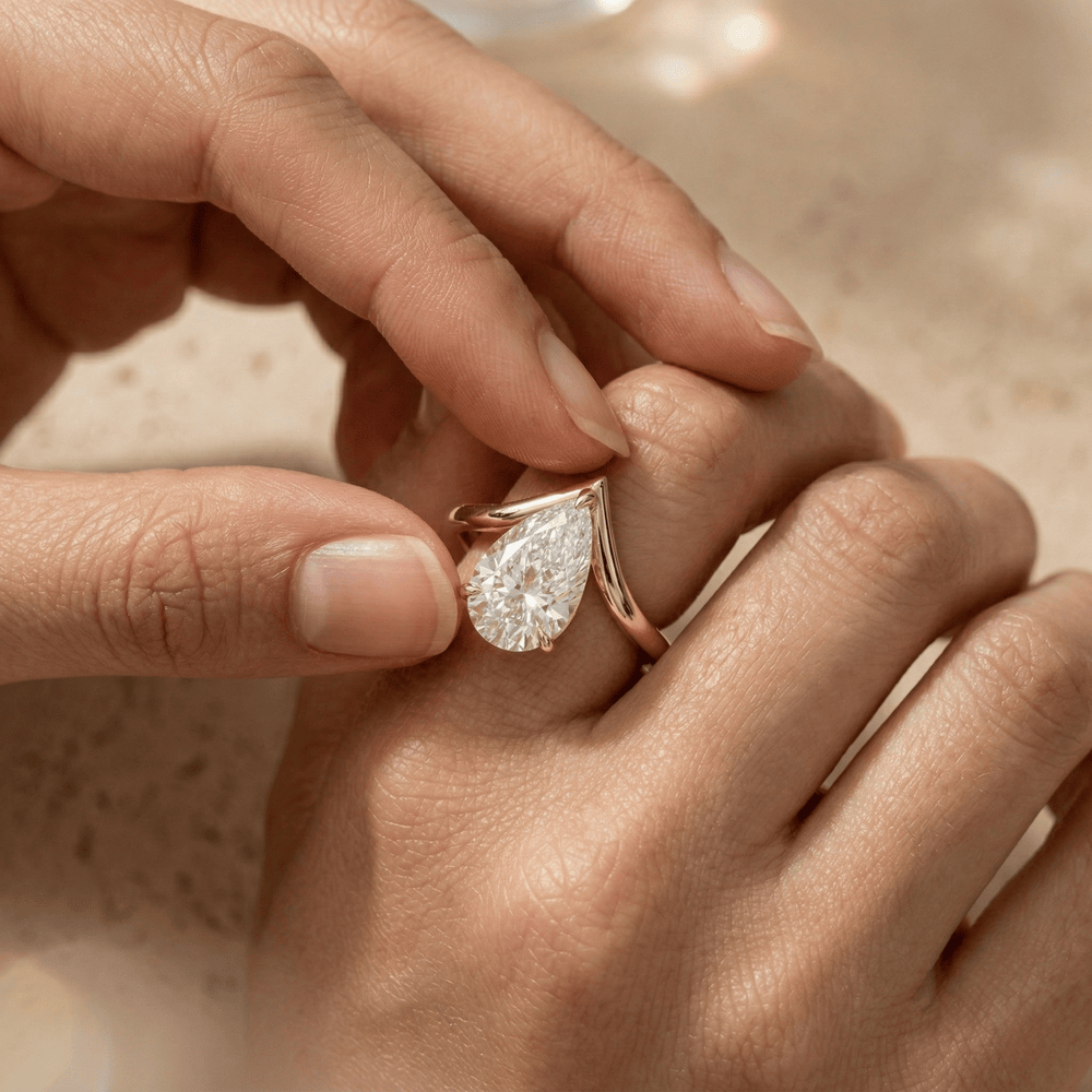 Curved gold engagement ring with pear shaped center diamond