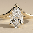 Curved gold engagement ring with pear shaped center diamond closup