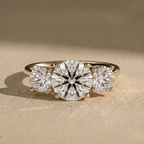 Three stone diamond ring with brilliant round center