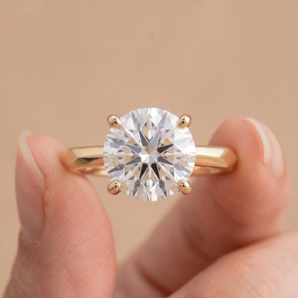 Round moissanite proposal ring with vintage detailing on finger