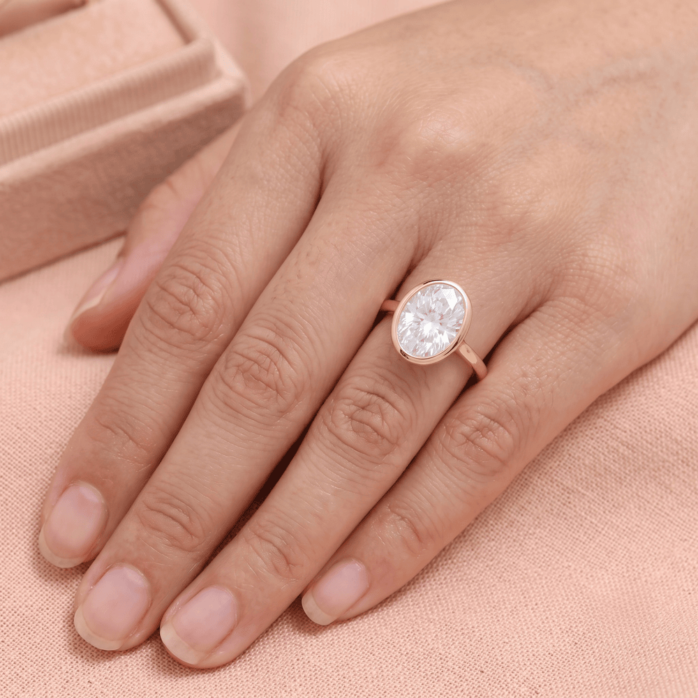 Solitaire bezel set oval diamond ring on hand