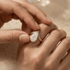 Curved gold engagement ring with pear shaped center moissanite