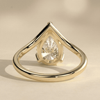 Curved gold engagement ring with pear shaped center moissanite