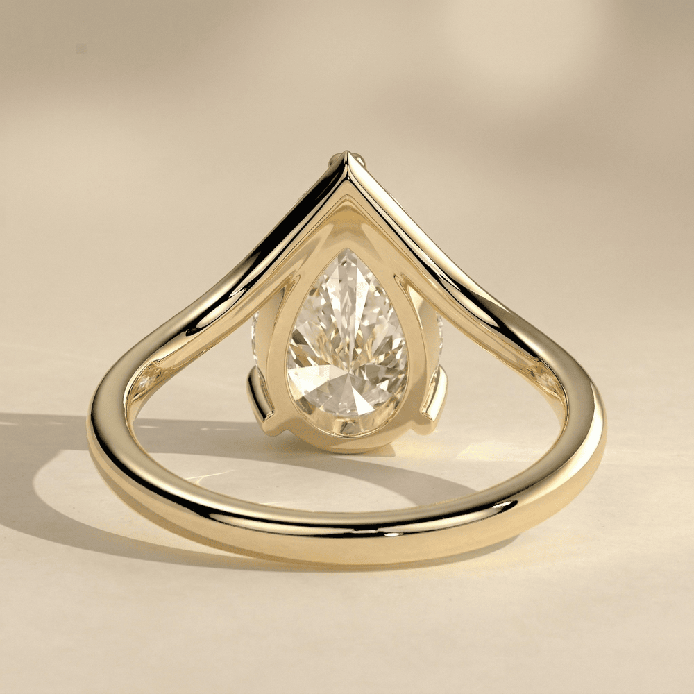 Curved gold engagement ring with pear shaped center moissanite